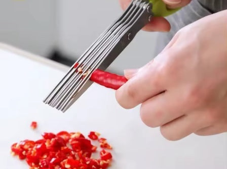 אדם חותך פלפל אדום באמצעות מספריים על רקע לבן