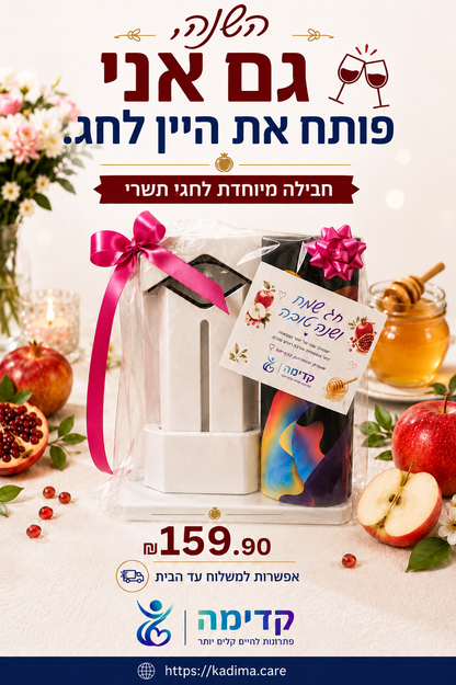 A festive gift basket containing a white candle and a colorful bottle, wrapped in clear cellophane with a pink ribbon, surrounded by apples, pomegranate, and honey on a decorated table. Hebrew text and the Kadima brand logo are prominently displayed.